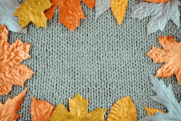 Autumn composition with golden leaves frame on knitted gray background