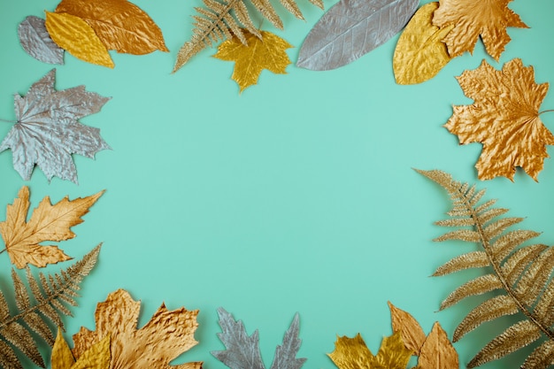 Autumn composition with golden leaves frame on mint 