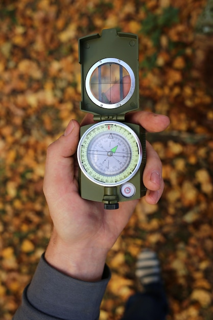 Autumn concept. Autumn travel. Compass in a male hand 