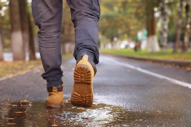 Autumn concept Pedestrian feet on the road Autumn leaves on the footpath