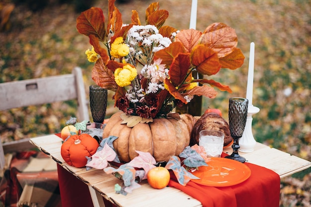 Autumn decor table setting in nature with pumpkin candles and flowers