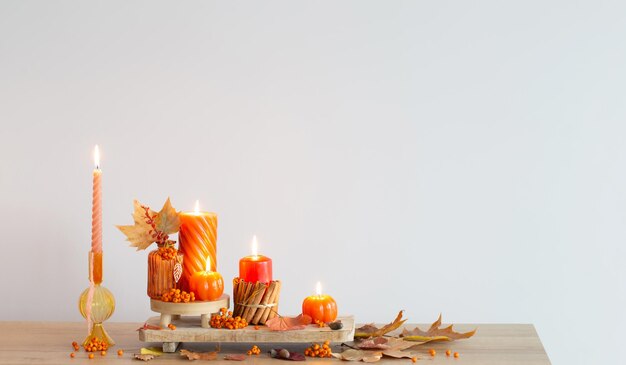 autumn decor with burning candles on wooden shelf