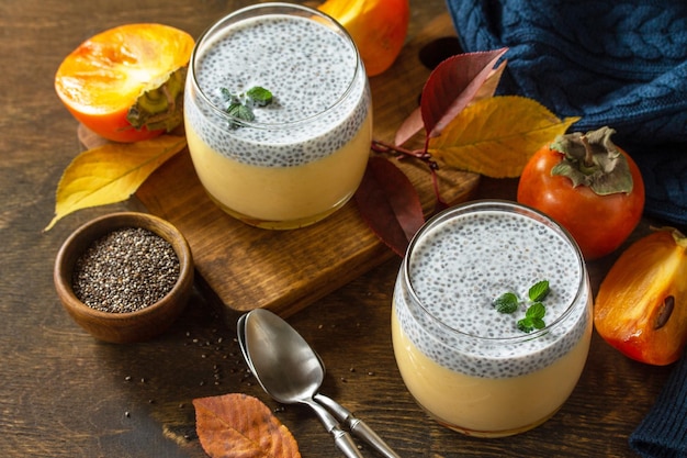 Autumn dessert Homemade panna cotta with persimmon fruit and chia seeds on a wooden table