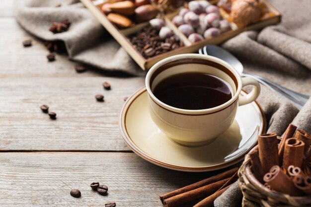 Autumn, fall, winter home decor in scandinavian, hygge style. Seasonal composition with cup of coffee, warm woolen scarf, soft plaid on a rustic wooden table.