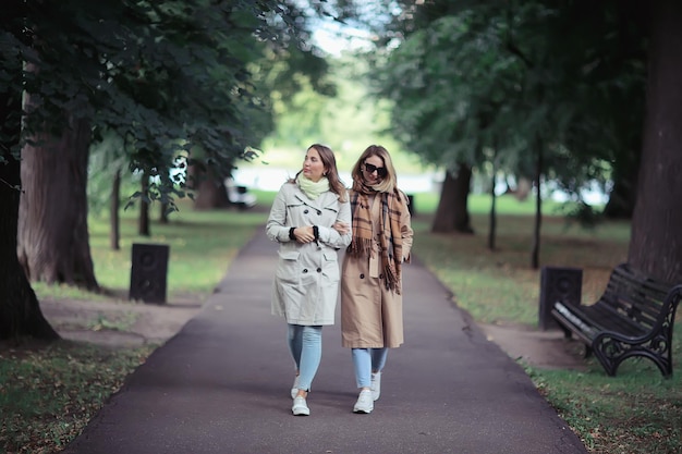 autumn fashion park girls two look / walk in a city park two glamorous fashionable girlfriends in a coat