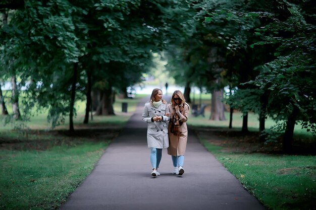 autumn fashion park girls two look / walk in a city park two glamorous fashionable girlfriends in a coat