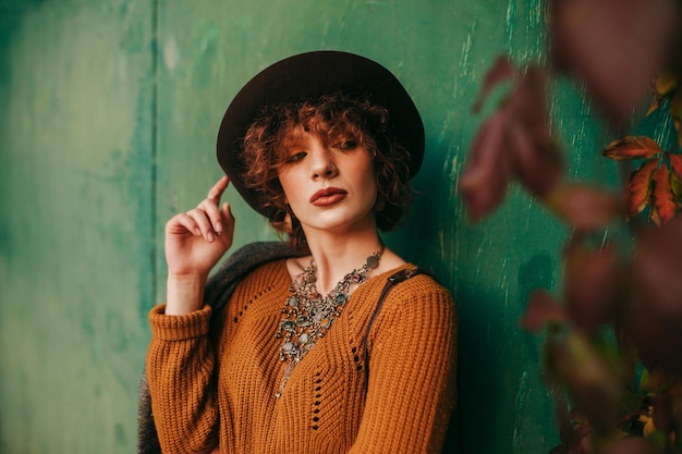 Autumn fashion portrait of a model with curly short hair on a green grunge background