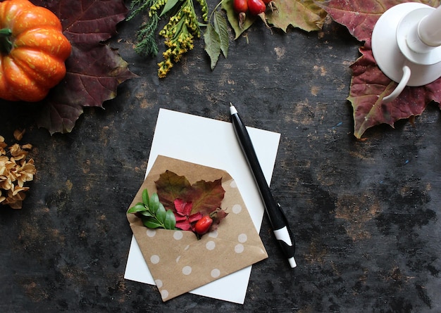 Autumn flat lay composition with blank paper card letter envelope coffee cup scarf fallen leaves on beige background Autumn hygge style desk table top view