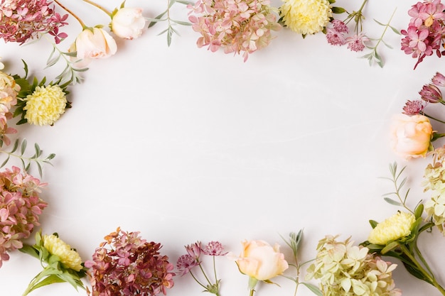 Autumn flowers composition. Frame made of pink rose, hydrangea flowers on white gray background. Flat lay, top view, copy space.