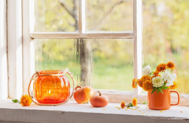 Autumn flowers and pumpkins on old white windowsill