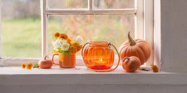 Autumn flowers and pumpkins on old white windowsill