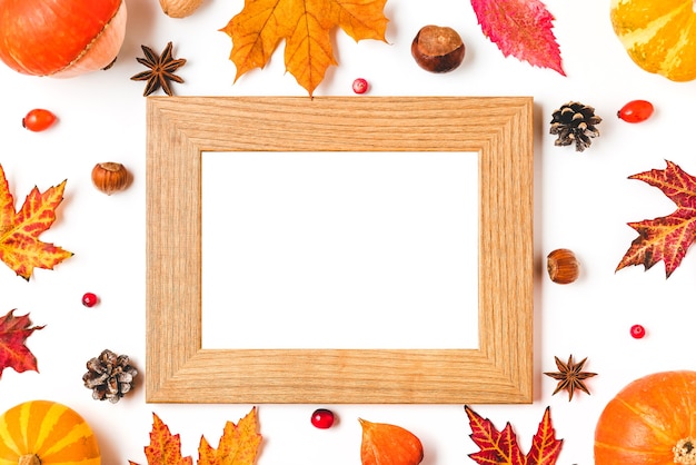 Autumn frame made of fall leaves, pumpkins, flowers, berries and nuts isolated