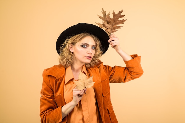 Photo autumn girl in black hat beautiful model girl with autumnal leaves sensual woman with autumn leaf in