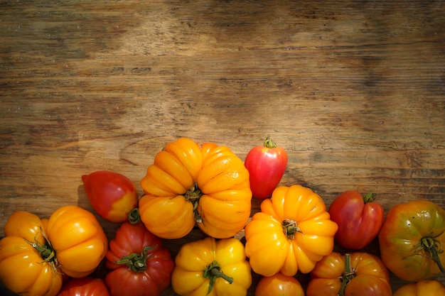 Autumn harvest food background Organic farm vegetables on wooden backdrop Fresh ripe yellow tomatoes