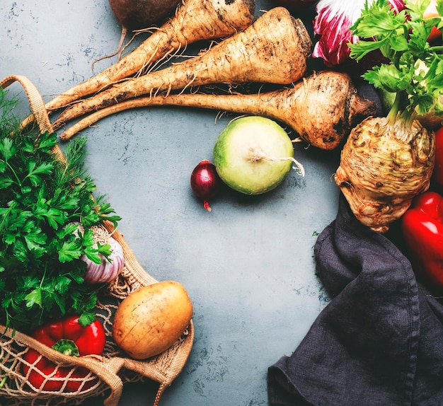 Autumn harvest food background with vegetables root celery radish parsnips paprika carrots on gray table Harvesting local farm market shopping healthy eating concept Top view