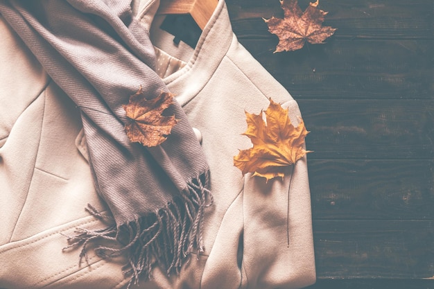 Autumn home cozy composition with a scarf and maple leaves on a wooden background