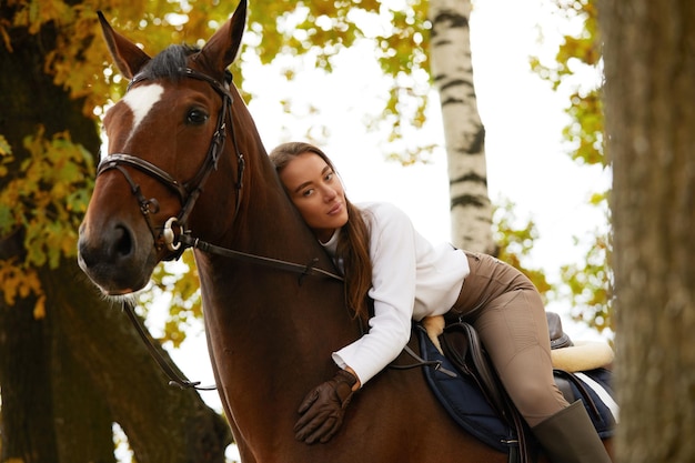 Autumn landscape beautiful brunette girl with long hair posing with a red horse in the forest