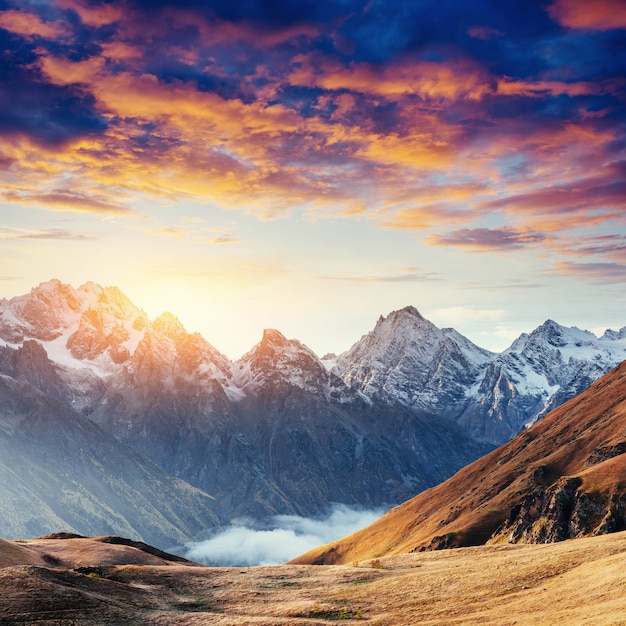 Autumn landscape and snowy mountain peaks. Fantastic sunset