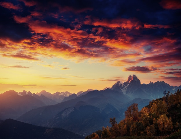 Autumn landscape and snowy mountain peaks. Fantastic sunset. 