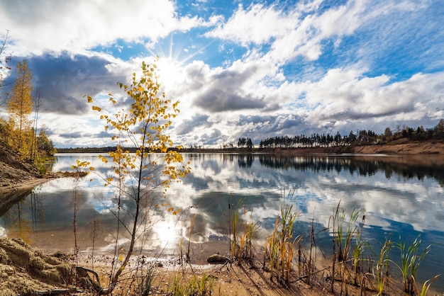 Autumn landscape with beautiful clouds over the lake with a mirror image.