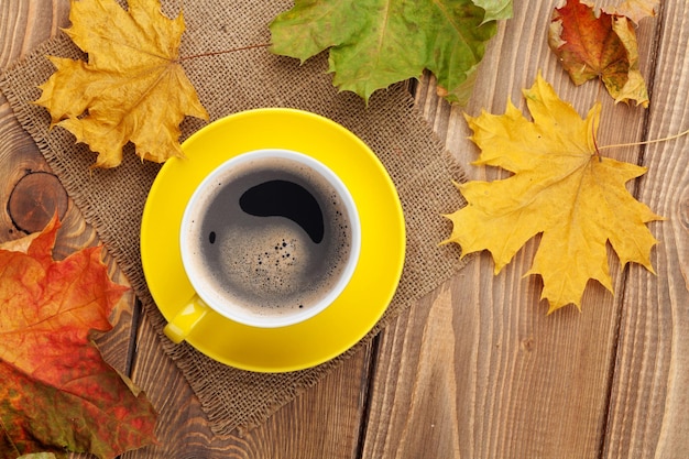 Autumn leaves and coffee cup over wood background