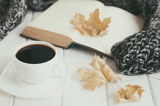 Autumn leaves cup of coffee warm knitted scarf open old book Cozy home reading Hygge mood