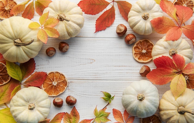 Autumn leaves and pumpkins over old wooden background