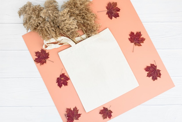 Autumn mockup with tote bag blank and dry reeds on white wood background