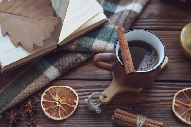 Autumn mood autumn atmosphere A cup of hot coffee a checkered plaid cinnamon sticks star anise a book on a wooden windowsill top view