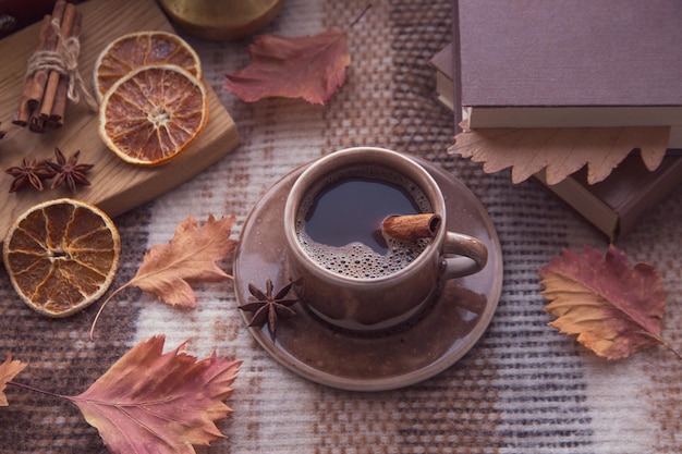 Autumn mood autumn atmosphere A cup of hot coffee cinnamon sticks star anise a book autumn leaves on a knitted plaid on a rainy day