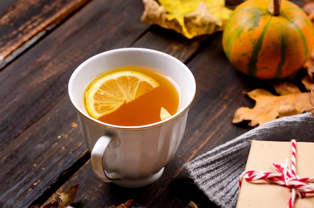 Autumn mood concept Hot tea with lemon and leaves on wooden background