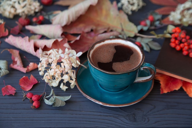 Autumn mood a cup of coffee among autumn leaves on a wooden dark table Texture of leaves and berries