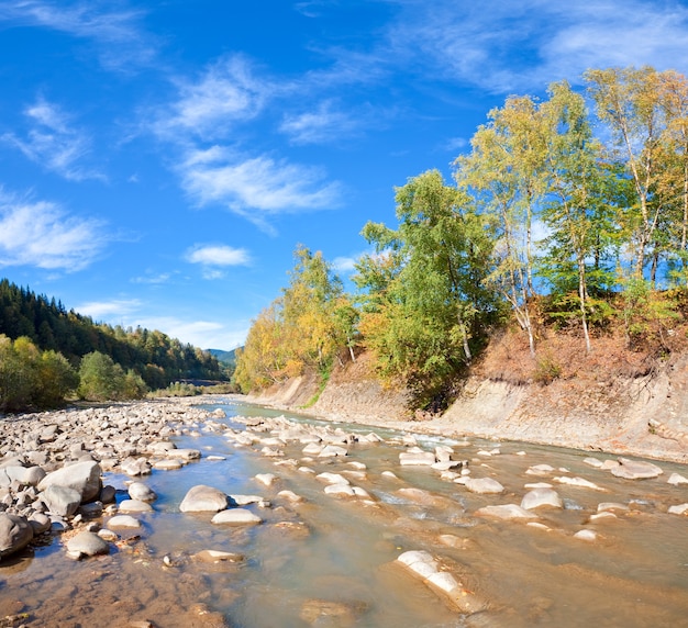 Autumn mountain stony river view with varicolored trees on riverside. Two shots stitch image.