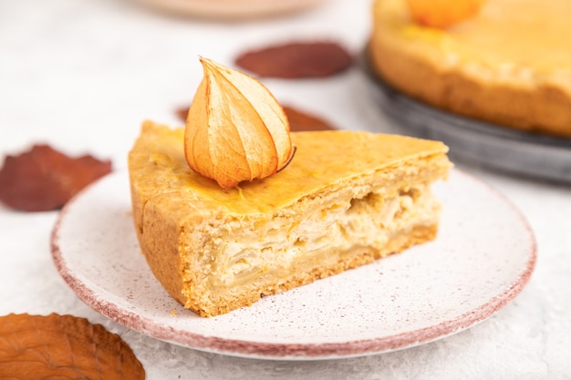 Autumn onion pie decorated with leaves and cup of coffee on gray concrete