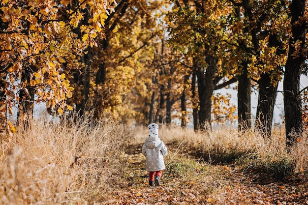 Autumn outdoor candid portrait of cute baby toddler girl in fall nature background little baby girl