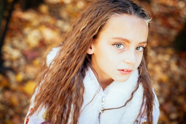 Autumn outdoor portrait of beautiful happy child girl walking in park in warm clothes