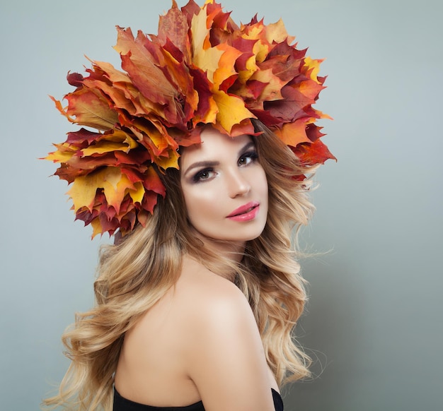 Autumn portrait of cute blonde woman Pretty model with autumn leaves makeup and long curly hair