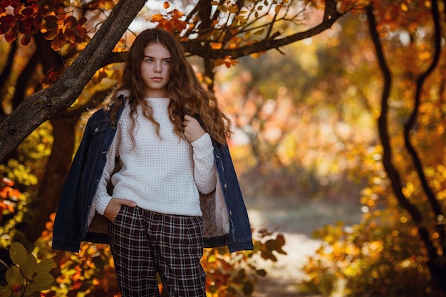 Autumn portrait of happy lovely and beautiful Caucasian girl in forest in fall colors Concept of autumn mood