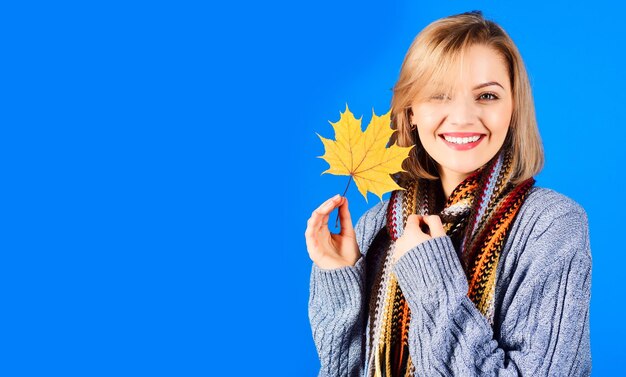 Autumn portrait of smiling woman with maple leaves happy girl in warm knitted sweater and scarf