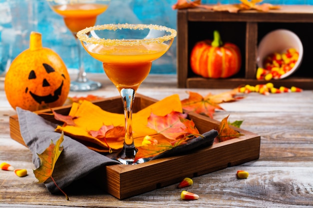 Autumn pumpkin margarita cocktail with halloween decor