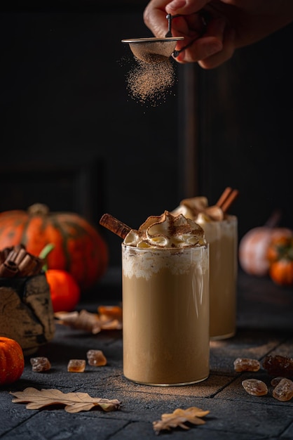 Autumn pumpkin spice latte with whipped cream and cinnamon on dark background