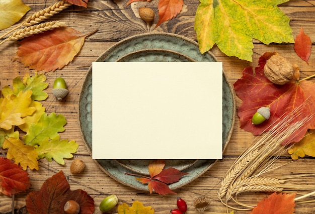 Autumn rustic table setting with blank card between leaves and berries top view mockup