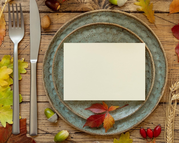 Autumn rustic table setting with blank card between leaves and berries top view mockup