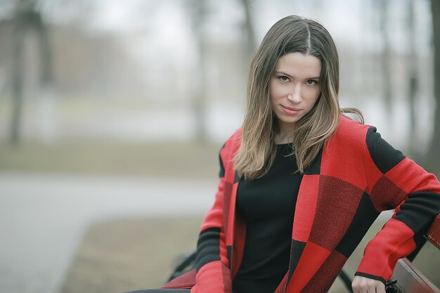 autumn sad girl outdoor / autumn weather, portrait of a young adult girl in a coat in a cage, Scottish style