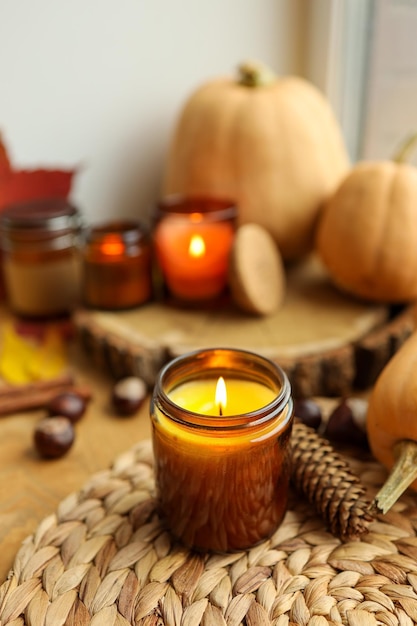 Autumn still life on the windowsill a burning candle pumpkins and candles