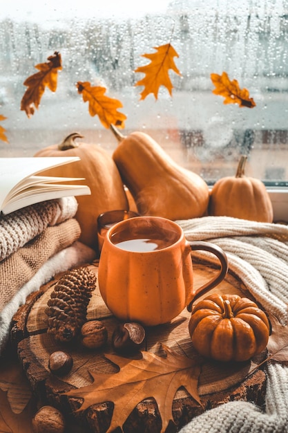 Autumn still life on the windowsill a cup of tea candles pumpkins leaves thanksgiving house interior