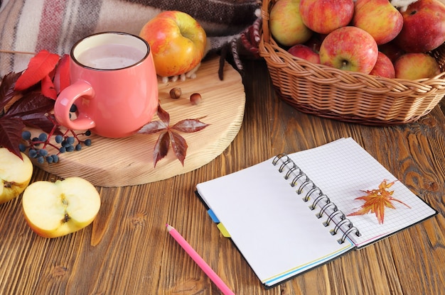 Autumn still life with a cup of cocoa, notebook and apple.