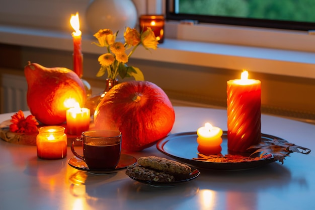 autumn still life with pumpkins burning candles and cup of tea