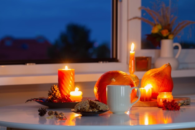 autumn still life with pumpkins burning candles and cup of tea