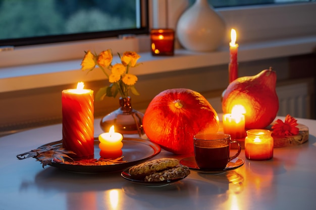 autumn still life with pumpkins burning candles and cup of tea